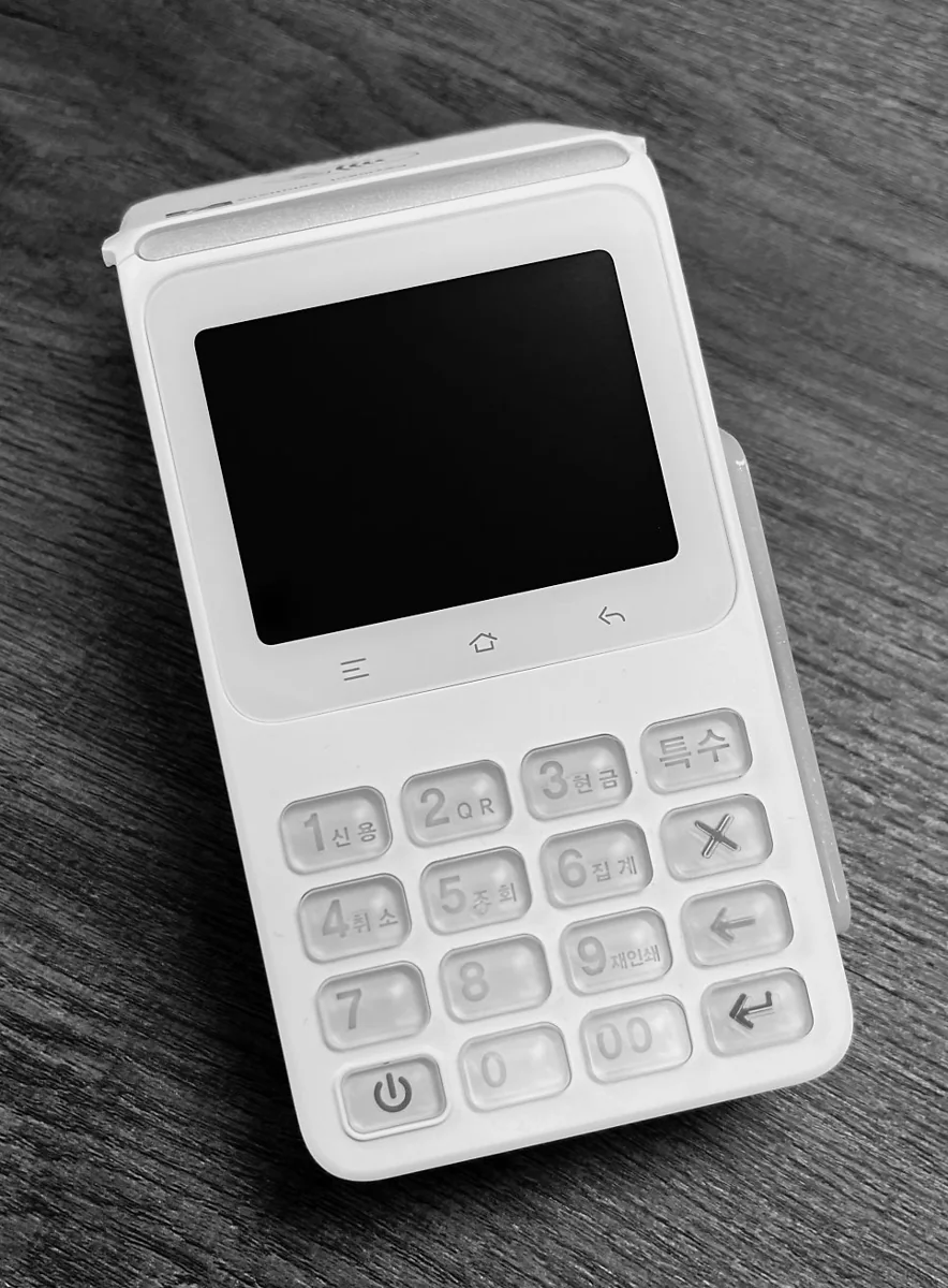 LC-D300 — 정면. 화면 아래 한글이 함께 새겨진 키패드가 있고, 위쪽 덮개 안이 영수증 프린터입니다.